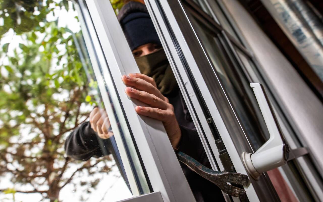 ILLUSTRATION - Ein Mann mimt einen Einbrecher und benutzt ein Brecheisen, um eine gekippte Terrassentür aufzuhebeln. Maßnahmen für privaten Einbruchschutz sollten nach Auffassung der SPD auch in Zukunft vom Land finanziell unterstützt werden. (zu dpa "SPD kritisiert Streichung der Mittel für privaten Einbruchschutz")