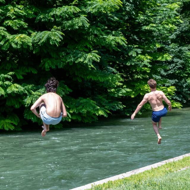 Zwei Jugendliche springen bei heißen Temperaturen zur Abkühlung in einen Fluss.