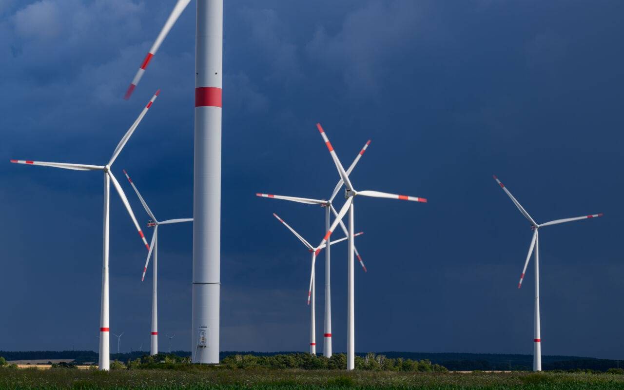 Dunkle Gewitterwolken ziehen über einen Windenergiepark.