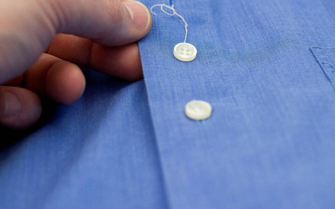 Bei einem Hemd hat sich am Knopf ein Faden gelöst