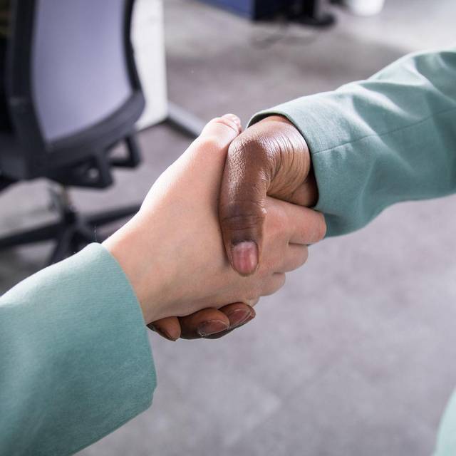 Zwei Personen reichen sich in einem Büro die Hand