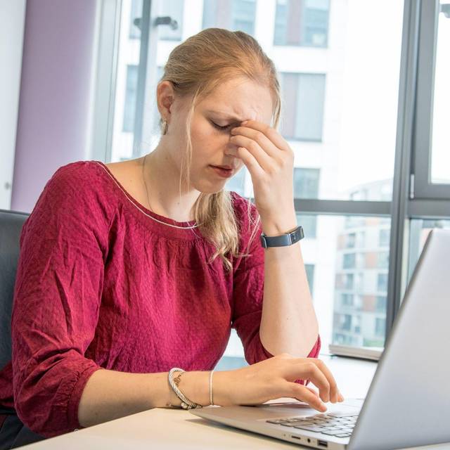 Eine Frau reibt sich die Augen am Arbeitsplatz