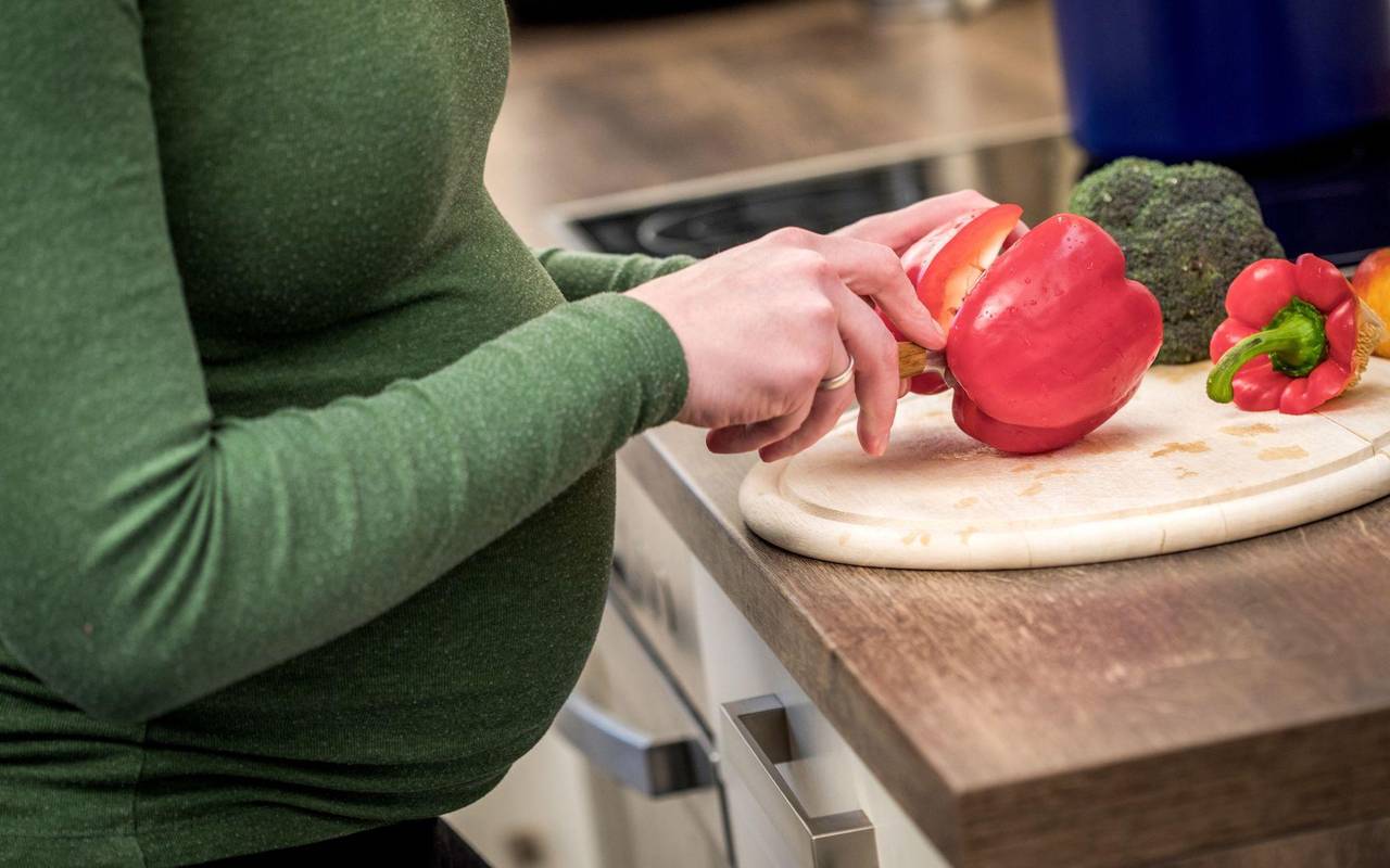 Schwangere Frau kocht mit Gemüse