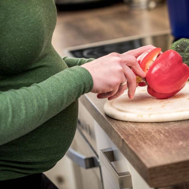 Schwangere Frau kocht mit Gemüse