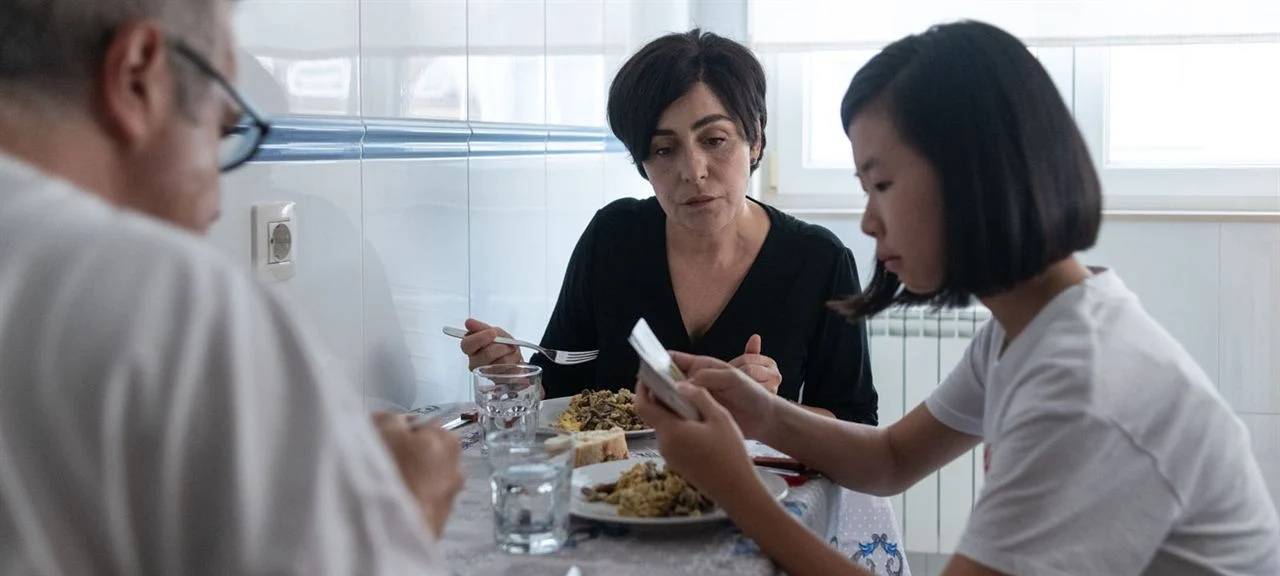 Asunta mit ihren Eltern am Essenstisch.