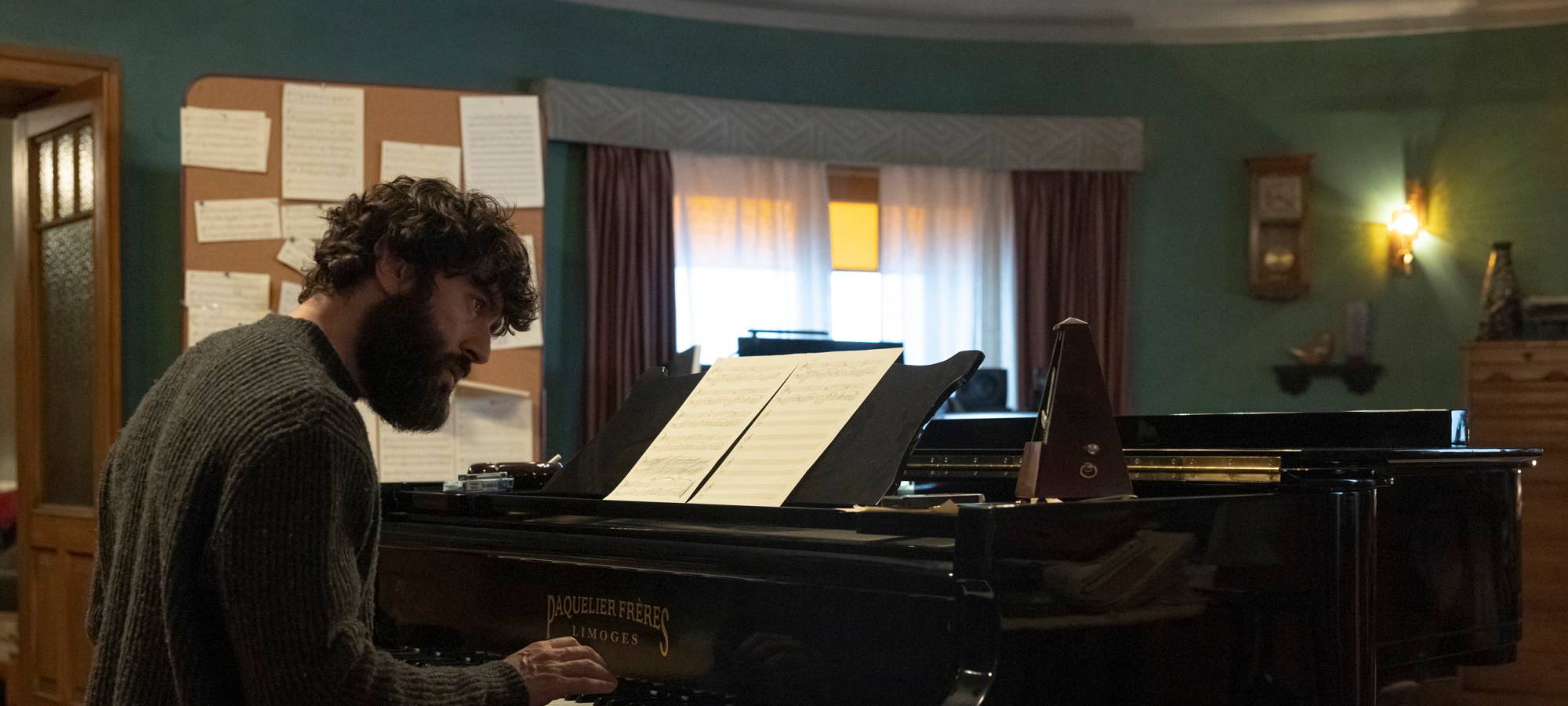 Harper sitzt am Piano.