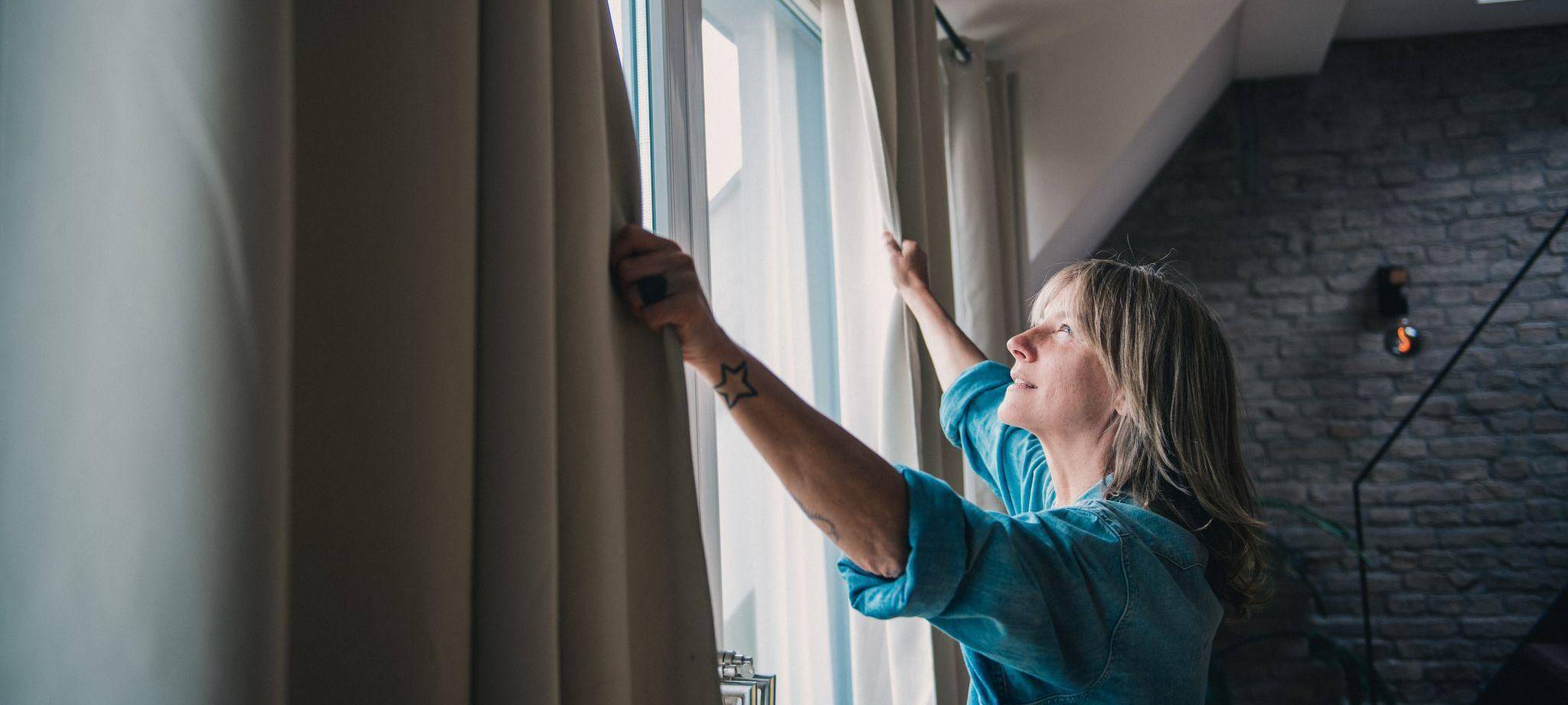 Eine Frau steht vor geöffneten Vorhängen