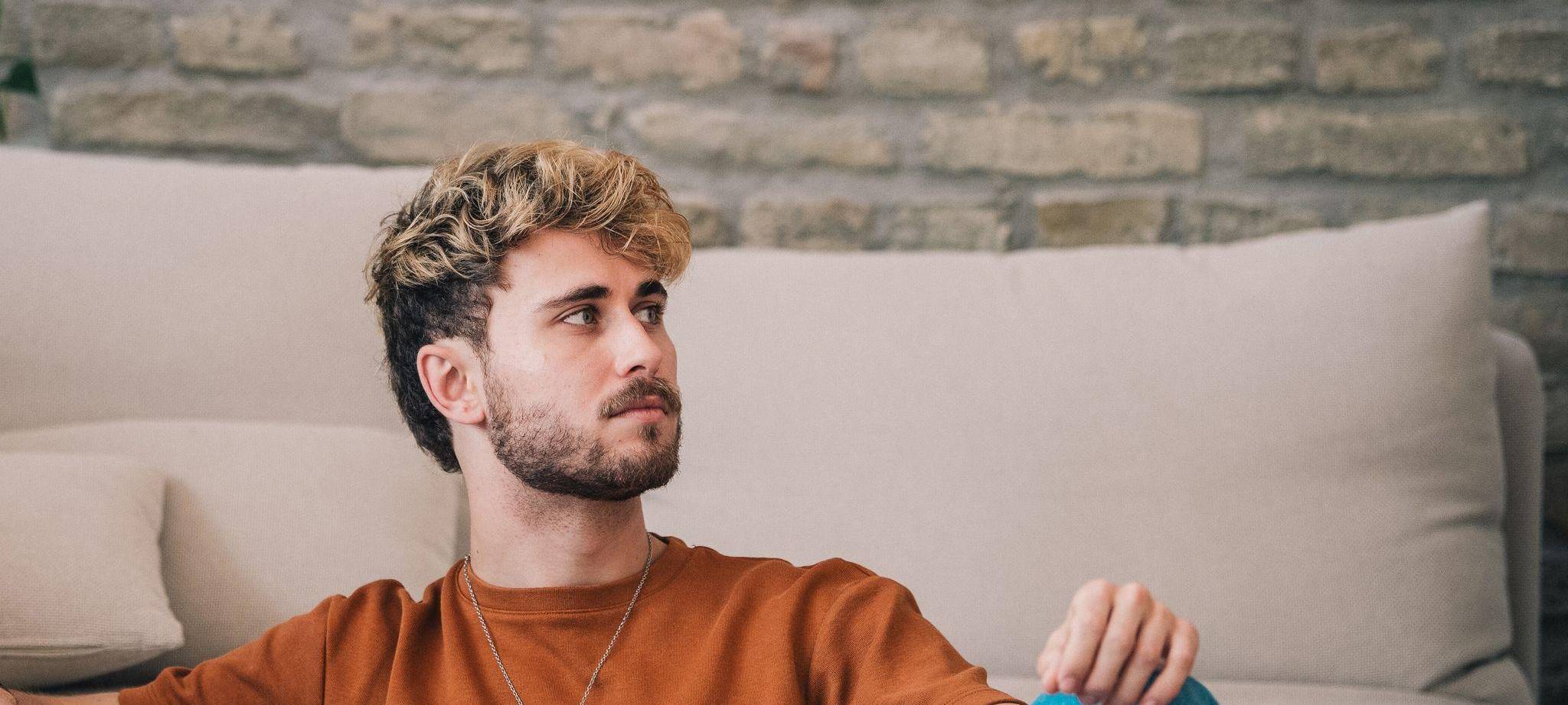 Mann sitzt nachdenklich in einem Wohnzimmer