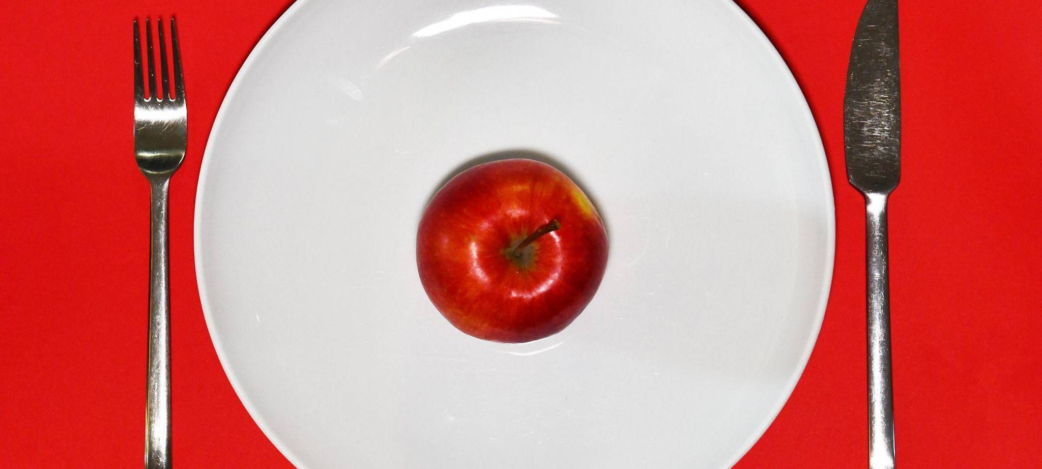 Ein Apfel liegt zum Verzehr bereit auf einem Teller