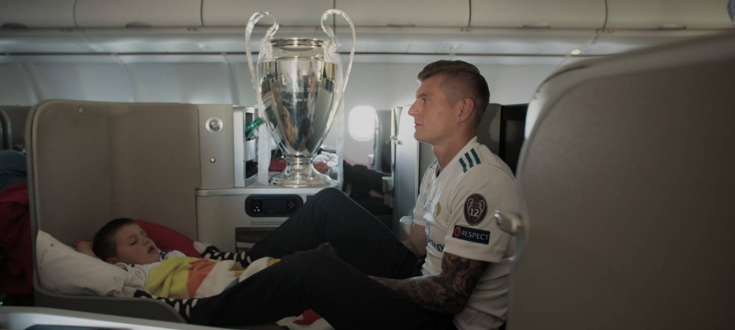 Toni Kroos sitzt im Flugzeug mit dem Champions League Pokal